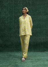 A model wearing a yellow silk pajama set with a mix of striped and polka dot patterns.